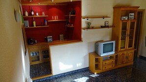 A living room with a television on a wooden stand, a cabinet with glass doors, and shelves with various items. - Gite in the Pyrenees (Guardiola de Berga)
