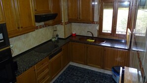 A kitchen with wooden cabinets, a granite countertop, a sink, and a window. - Gite in the Pyrenees (Guardiola de Berga)