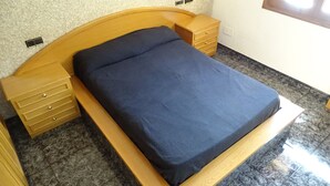 A bed with a wooden headboard and footboard, a dark blue mattress, and wooden nightstands with drawers. - Gite in the Pyrenees (Guardiola de Berga)