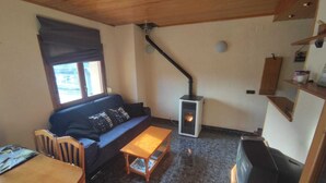 A cozy living room with a sofa, wooden coffee table, and a fireplace. - Gite in the Pyrenees (Guardiola de Berga)