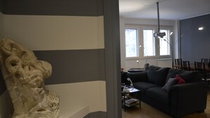 A living room with a stone sculpture, a dark sofa, a coffee table, and a lamp. - Large apartment with 2 bedrooms and two bathrooms in PALAZZO SAN MATTEO (Palermo)