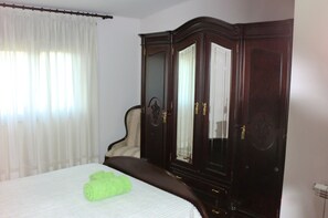 Una habitación de hotel con cama, un armario grande y una ventana con cortinas.