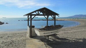 Een strand met een houten constructie waarop 'Andres Maricourt' staat.