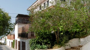 Een twee verdiepingen tellend huis met een balkon, een trap naar de ingang en een tuin met beplanting.