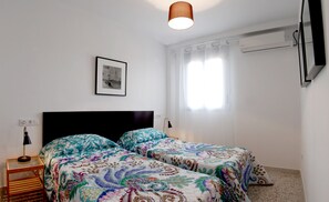 Camera da letto con due letti, un quadro appeso al muro, una lampada a soffitto e un condizionatore d'aria.