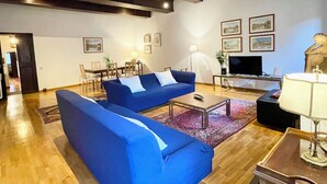 A living room with a blue sofa set, a coffee table, a TV, and a lamp.
