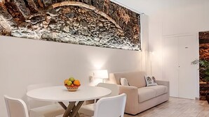 A modern living room with a round dining table, white chairs, a beige sofa, and a decorative wall piece. - Apollo Home "Cozy and independent home near the Ursino Castle" (Catania)