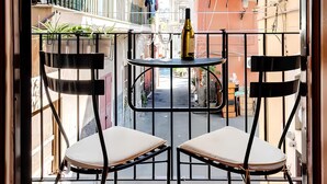 An outdoor balcony with two chairs and a table, overlooking a narrow street with buildings. - Apollo Home "Cozy and independent home near the Ursino Castle" (Catania)
