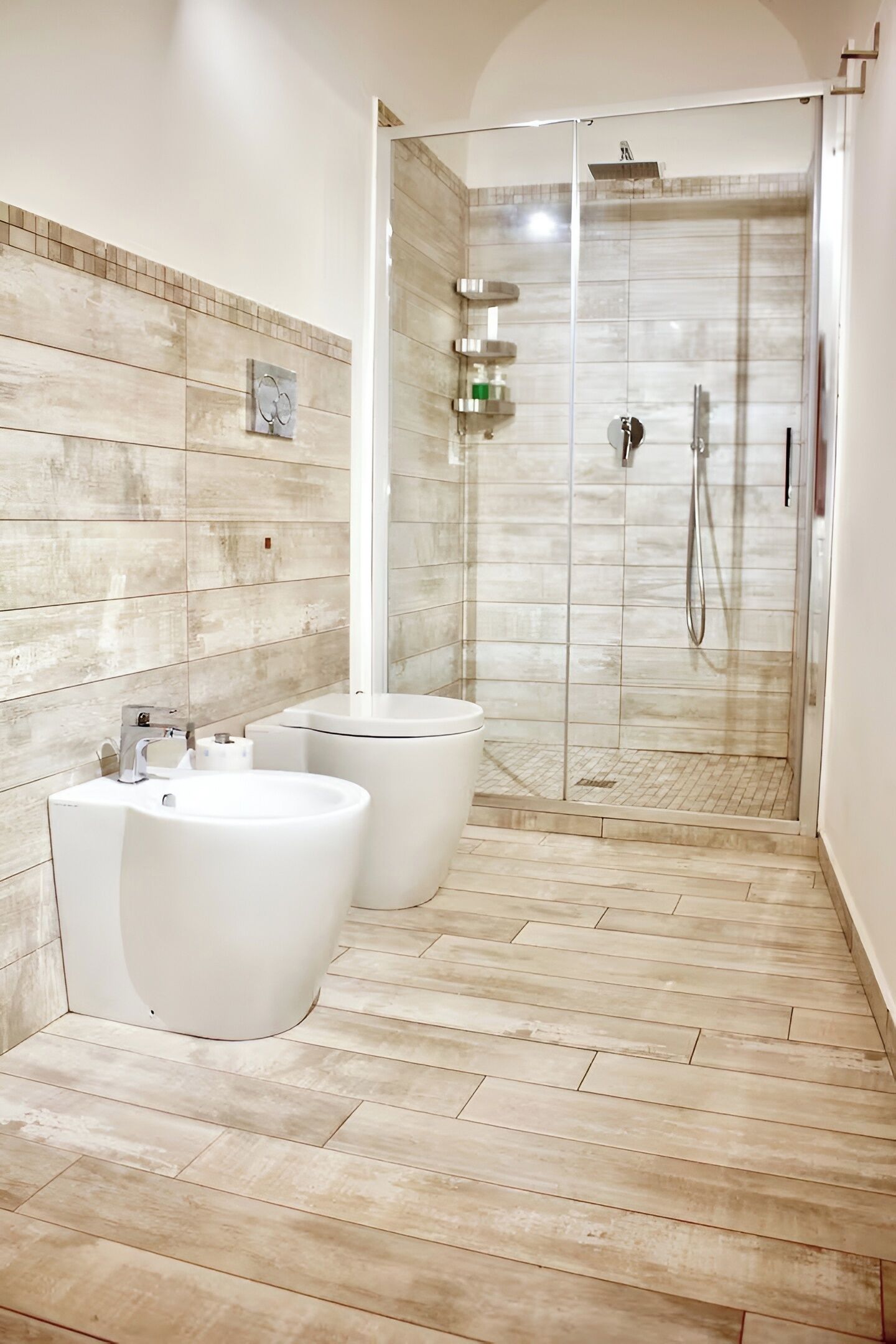 A modern bathroom with a walk-in shower, two sinks, and a tiled floor.