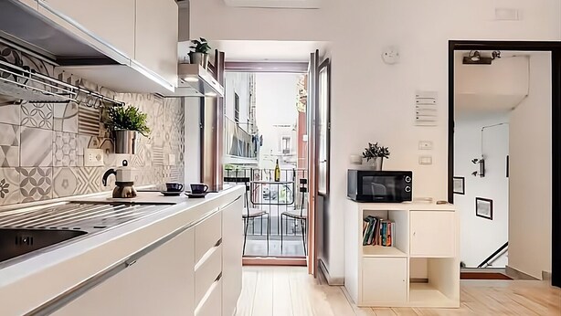 A modern kitchen with a central island, a microwave, and a small bookshelf. - Apollo Home "Cozy and independent home near the Ursino Castle" (Catania)