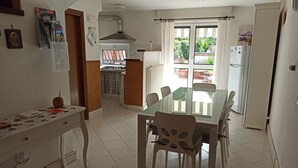A kitchen with a dining table and chairs, a refrigerator, and a window with curtains. - Amaryllis vacation homes - pink house - CODE CIN: IT011002B4COYDJRPS (Romito Magra)