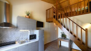 A kitchen with a microwave, toaster, and refrigerator. There is a wooden staircase leading to an upper level.