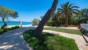 A stone pathway leading to a beach with a fence and palm trees.