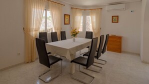 A dining area with a white table, black chairs, and a vase of yellow flowers.