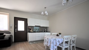 Een moderne keuken met witte kastjes, een eettafel met bloemendessin en een kroonluchter.