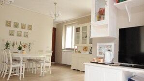 Een moderne woonkamer met een eethoek, witte kasten, een flatscreen televisie en een keuken met een radiator.