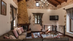 A cozy living room with a stone fireplace, a sofa, a coffee table, and a television.
