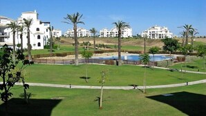 A resort with multiple white buildings, a large grassy area, and a swimming pool. - 2 Bed Apartment On PGA Golf Course (Sucina)