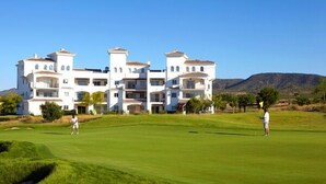 A golf course with a large white building in the background. - 2 Bed Apartment On PGA Golf Course (Sucina)