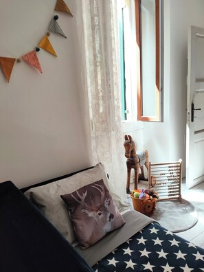 A bedroom with a bed, a window with curtains, a wooden horse decoration, and a wooden toy chest. - SWEET FLAT, new, refined, silent and in the center WIFI FIBER OPTIC (Verona)