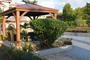 A wooden gazebo with a metal roof, surrounded by well-maintained hedges and flowering plants. - A superb 3-bedrooms Holiday Villa, mins away from Ocho Rios vibrant Town Centre (Tower Isle)