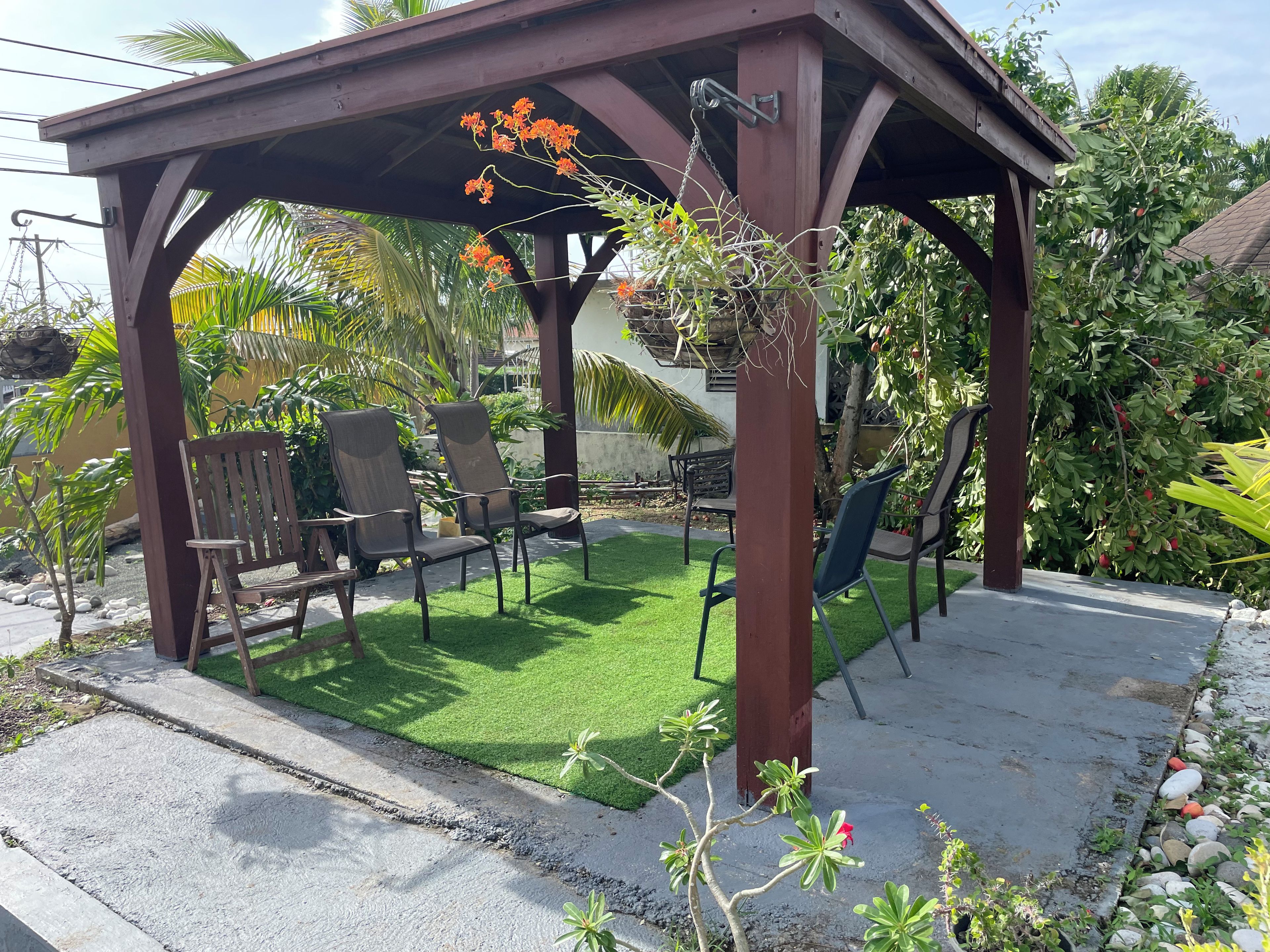 A covered patio area with a wooden pergola, outdoor seating, and a well-maintained lawn.