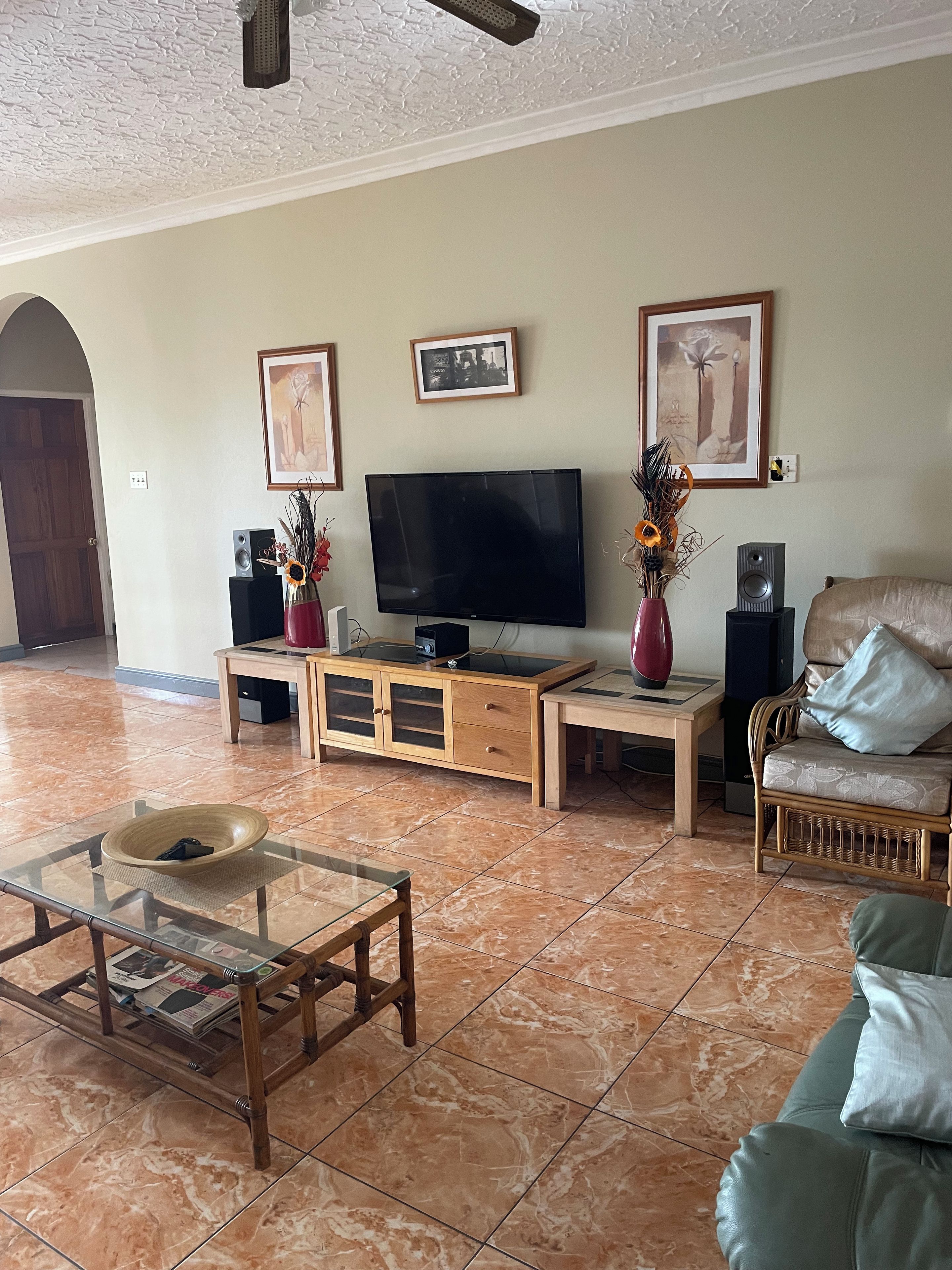 A living room with a television, a wooden cabinet, a glass coffee table, a sofa, and a fireplace.