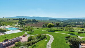 A pool area with a table set for dining, surrounded by a well-maintained lawn and garden paths. - Poderina dei Poggi 12, Emma Villas (I Poggi)