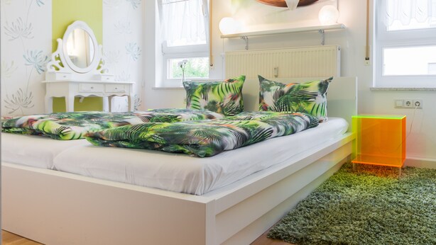 Un dormitorio con cama, mesita de noche, cómoda, espejo y ventana.