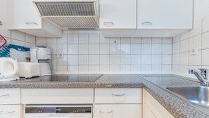 Una cocina moderna con armarios blancos, encimera de granito, lavavajillas integrado y pileta de acero inoxidable.