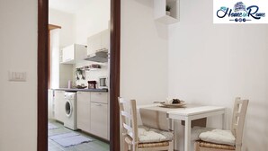 Una cocina compacta con lavadora, una mesa de comedor con dos sillas y un mueble pequeño.