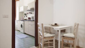 Una cocina compacta con lavadora, una mesa de comedor con dos sillas y un mueble pequeño.