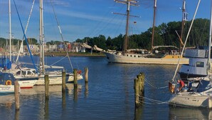 A marina with several sailboats docked, wooden pilings, and a building with flags in the background. - Family-friendly house with dunes, view of ocean, sauna (Lübeck)
