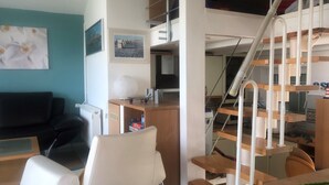 A modern living room with a sofa, a chair, a table, and a staircase. - Family-friendly house with dunes, view of ocean, sauna (Lübeck)