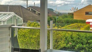 A balcony with a view of a residential area, including houses and a distant ship. - Family-friendly house with dunes, view of ocean, sauna (Lübeck)