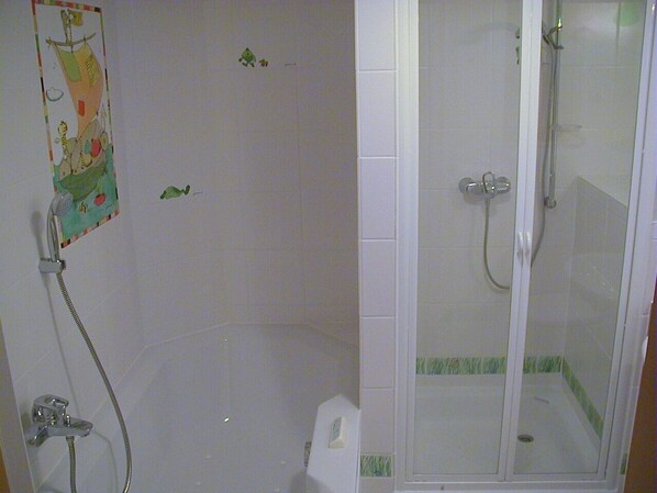 A shower area with a glass door, a showerhead, and a wall-mounted faucet. - Family-friendly house with dunes, view of ocean, sauna (Lübeck)