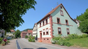 A traditional European-style building with a steep gable roof, multiple windows, and a brick facade.