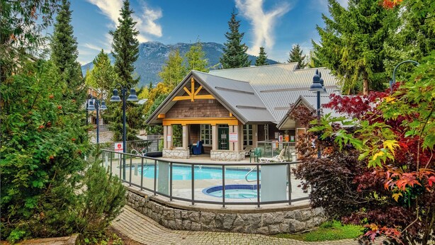 A lodge with a pool, surrounded by trees and mountains.