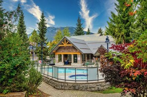 Un chalet doté d’une piscine, entouré d’arbres et de montagnes.