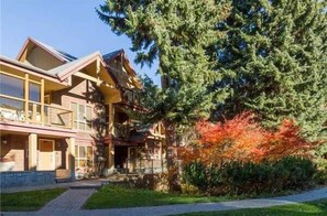 Situated in a serene natural setting, this lodge features a traditional facade and a balcony overlooking lush greenery.