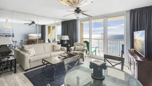 A modern living room with a large window, a ceiling fan, a sofa, a coffee table, and a TV.