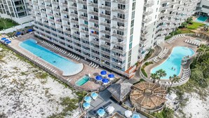 A high-rise hotel with multiple balconies, a central swimming pool, and a separate pool area.
