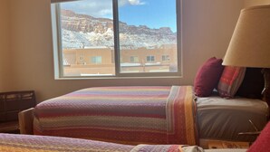 A hotel room with two beds, a window with a mountain view, and a lamp on the right side. - 1A4 Shared Pool, Private Patio, Garage, Close to Arches (Moab)