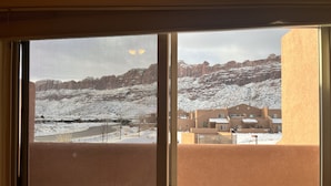 A view through a sliding glass door of a building with a snow-covered landscape and a clear sky. - 1A4 Shared Pool, Private Patio, Garage, Close to Arches (Moab)