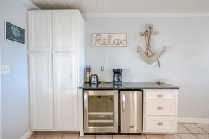 Cocina con armarios blancos, refrigerador de acero inoxidable, cafetera y un adorno de ancla en la pared.