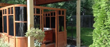 A wooden outdoor hot tub area with a wooden deck, a bench, and a hot tub.
