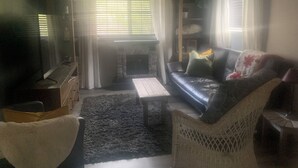 Una sala de estar con chimenea, un sofá, una mesa de centro y una televisión.