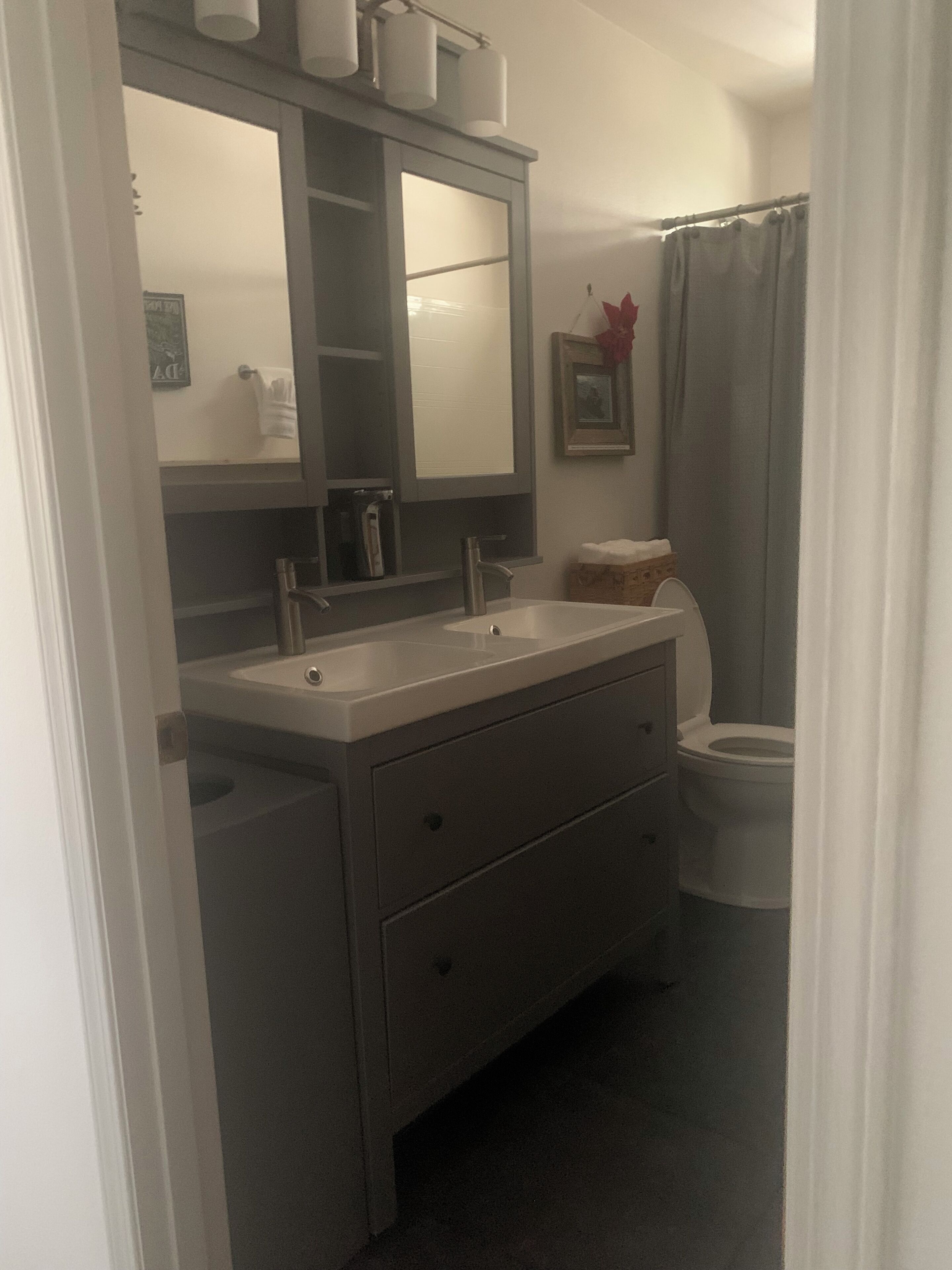 Een badkamer met een wastafel met dubbele wastafels, een toilet en een douchegordijn.