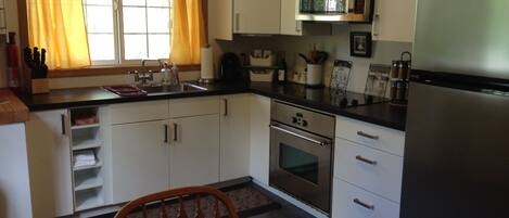 A compact kitchen with white cabinets, a stainless steel oven, a microwave, and a refrigerator.