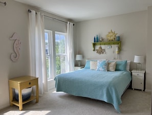 Une chambre à coucher comprenant un lit, une table de chevet, une fenêtre avec des rideaux et une étagère murale ornée d’objets décoratifs.